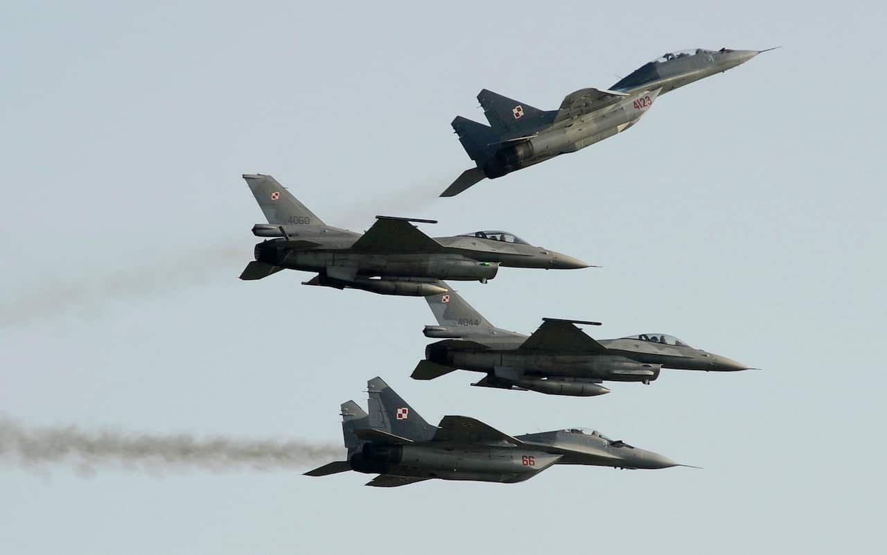 Two Polish Air Force Russian made Mig 29's fly above and below two Polish Air Force U.S. made F-16's fighter jets during the Air Show in Radom, Poland