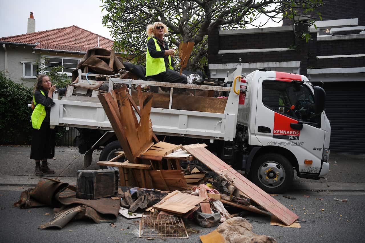 Flood effected residents of Lismore unload a dump truck of household flood damaged items and carry it on foot after police blocked their truck destined for the Prime Ministers residence of Kirribilli House in Sydney, Monday, March 21, 2022. (AAP Image/Dea