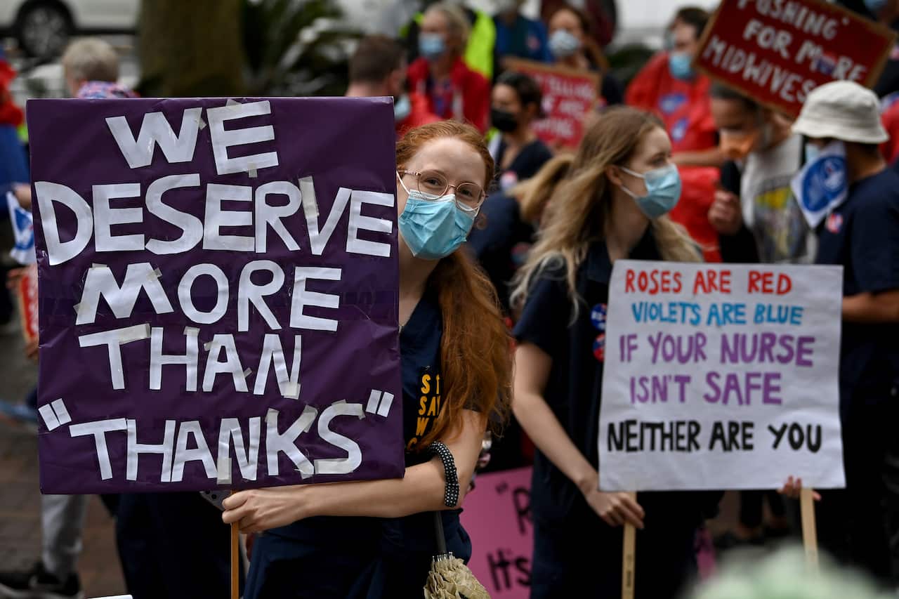 Nurses and midwives hold placards during a nurses strike rally at NSW Parliament House in Sydney, Thursday, March 31, 2022. Nurses and midwives plan to walk off the job for 24-hours after the NSW government failed to address ongoing staffing issues at pub