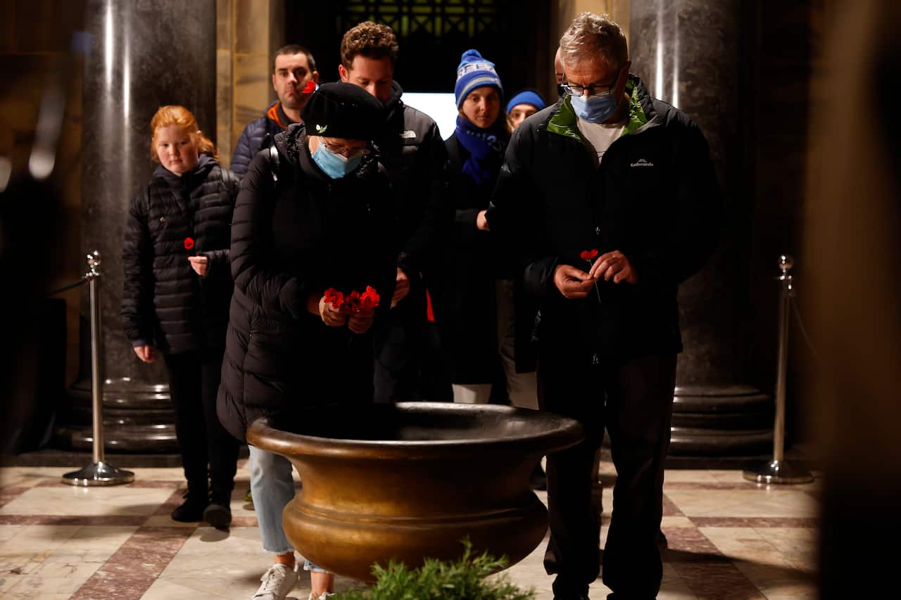 People are seen in the Sanctuary at the Shrine of Remembrance placing poppies during Anzac Day in Melbourne, Monday, April 25, 2022. 
