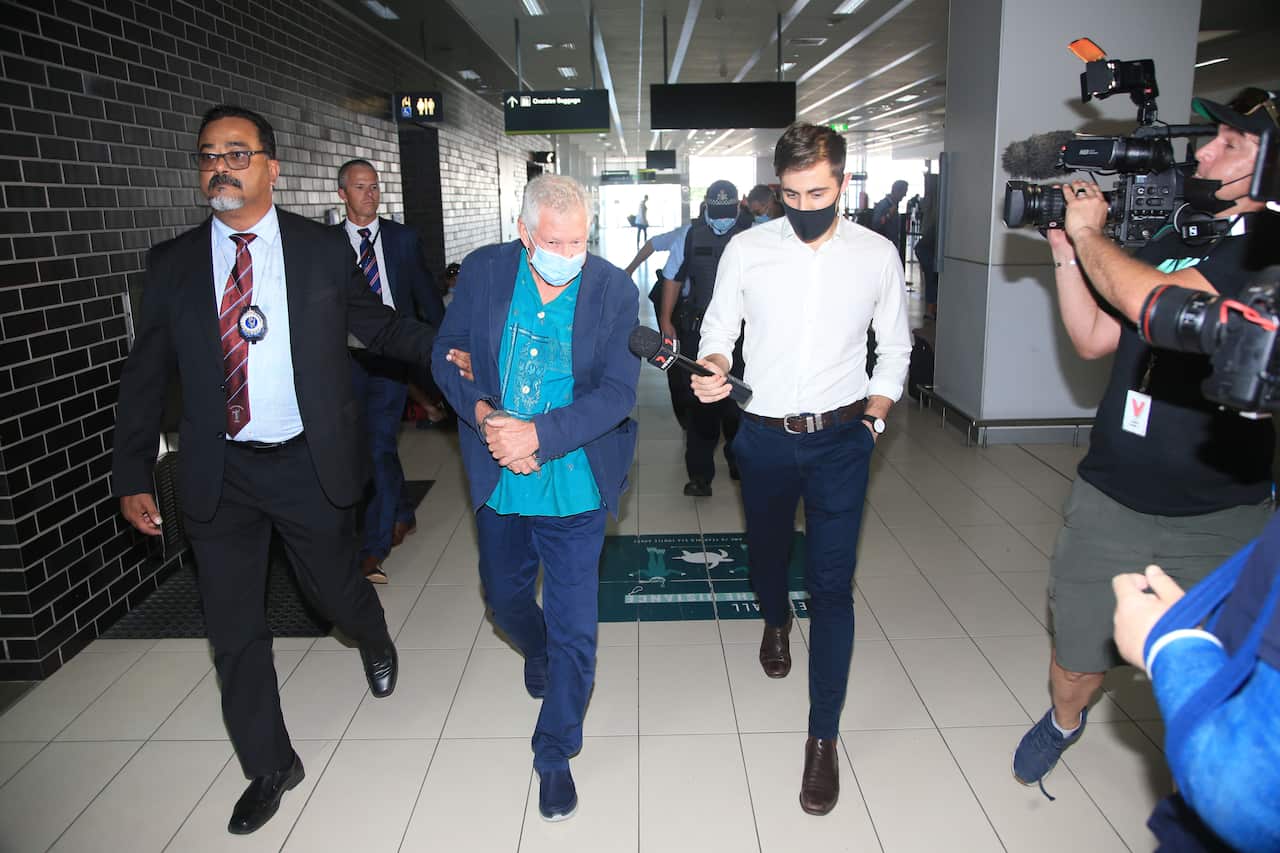 Superyacht Tour Operator James Blee is placed in handcuffs by police to be extradited from Queensland via Cairns Airport, in Cairns, Friday, May 13, 2022. (AAP Image/Justin Brierty) NO ARCHIVING