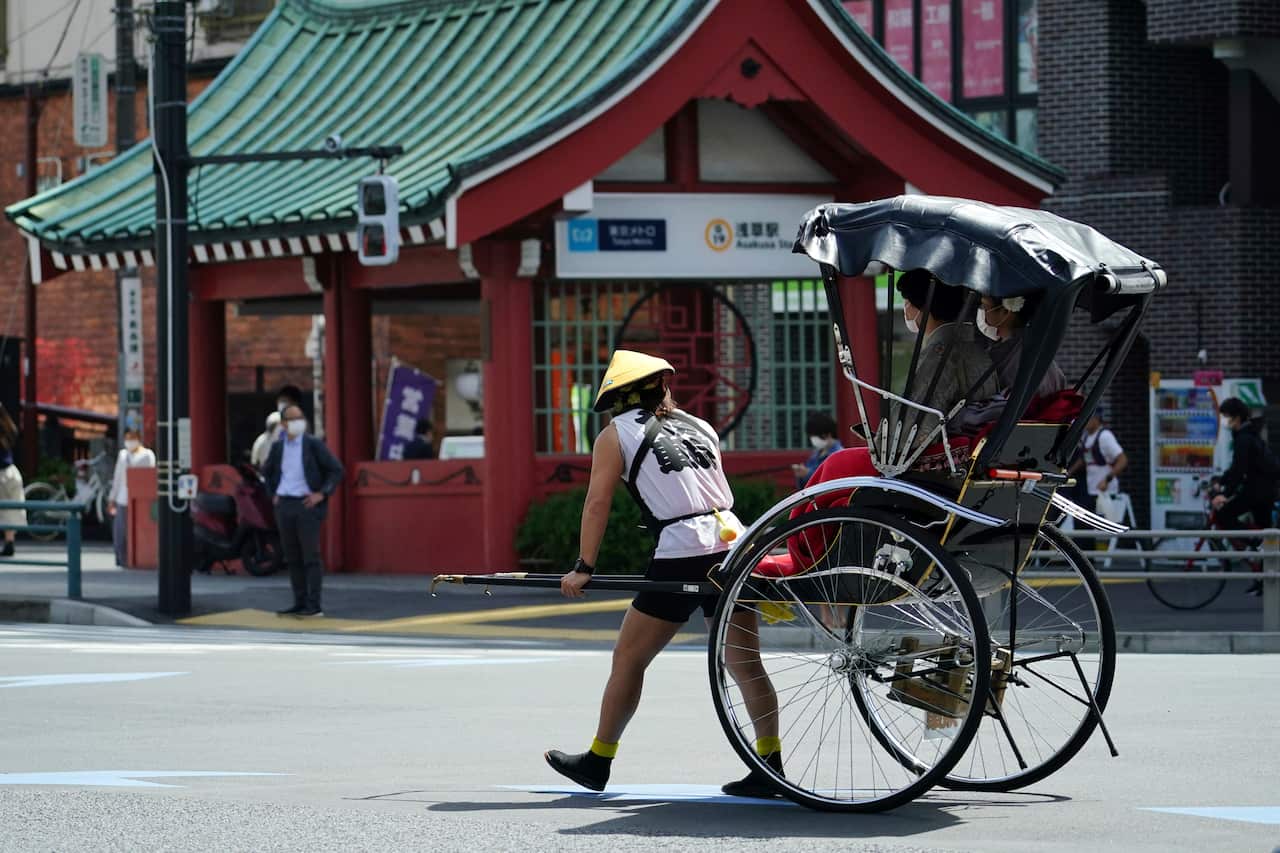 FILE - A rickshaw puller carries tourists near Sensoji Buddhist temple at Tokyo's Asakusa district in Tokyo, March 31, 2021. (AP Photo/Eugene Hoshiko, File)                                            