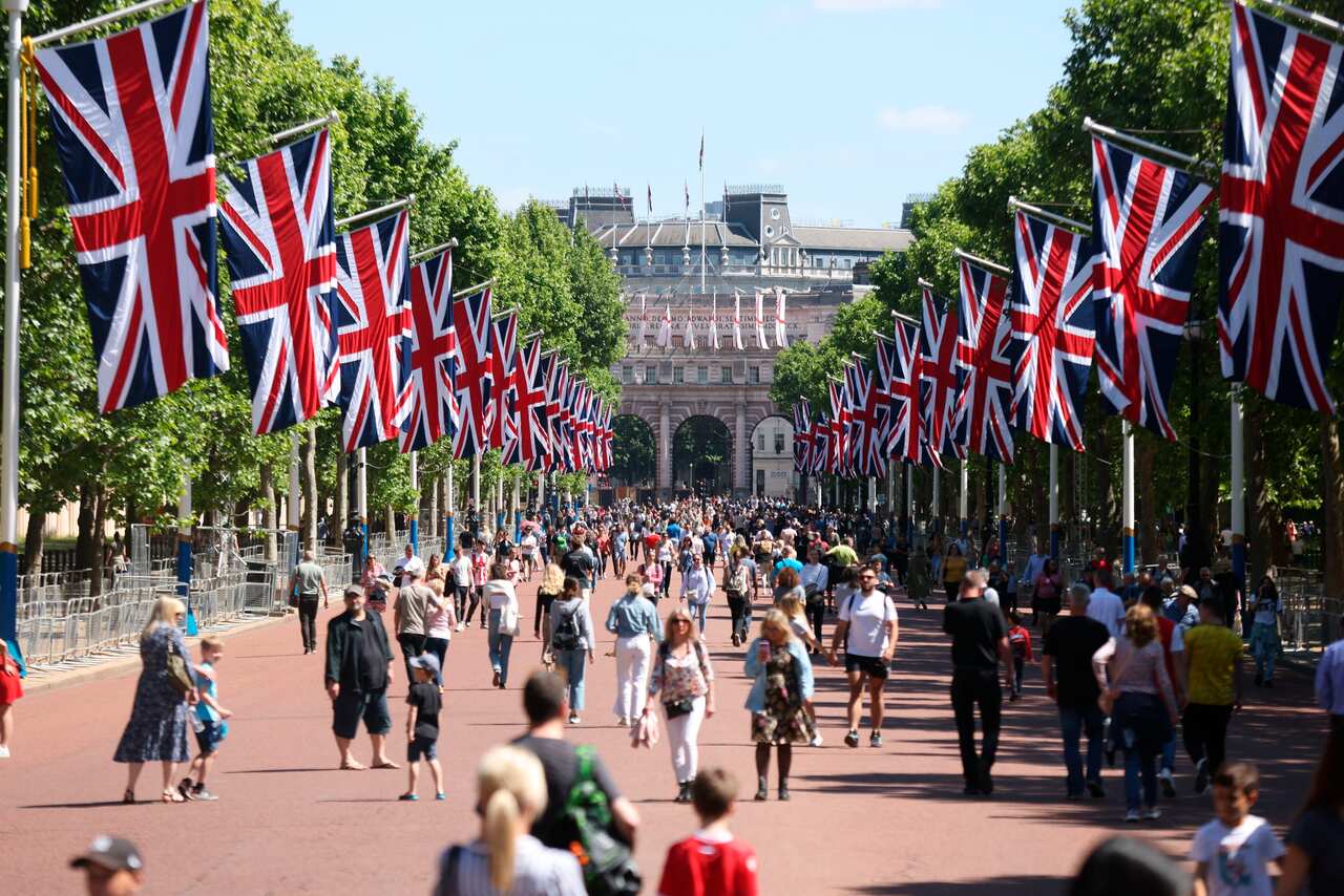 People walk along The Mall, decorated for the upcoming Platinum Jubilee of Britain's Queen Elizabeth II, in London, Sunday, May 22, 2022. (James Manning/PA via AP)