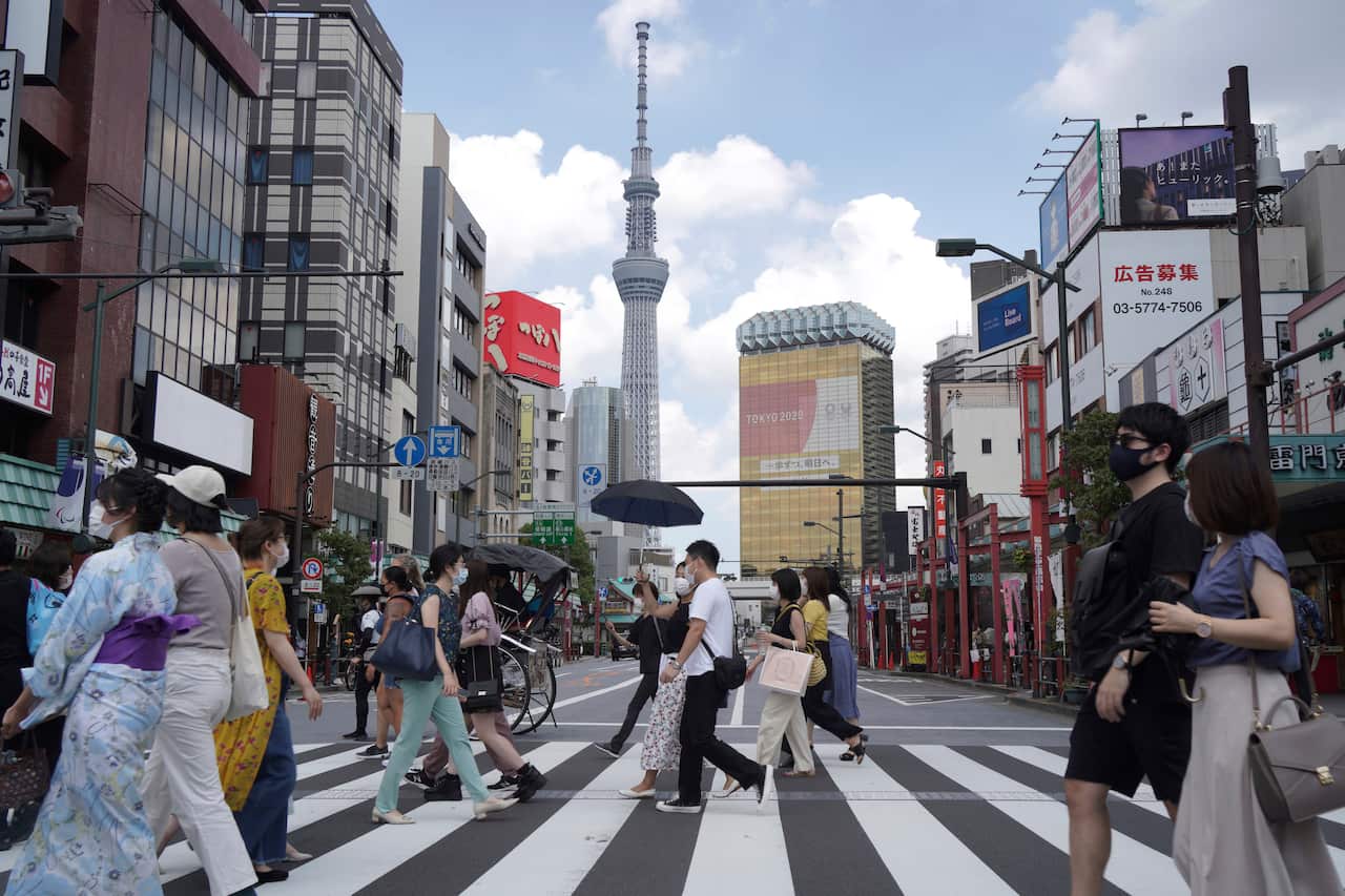 People walk along a pedestrian crossing in the tourist district of Asakusa, near the landmark Tokyo Skytree tower in Tokyo, Japan on Saturday, July 31, 2021. (AP Photo/Kantaro Komiya)