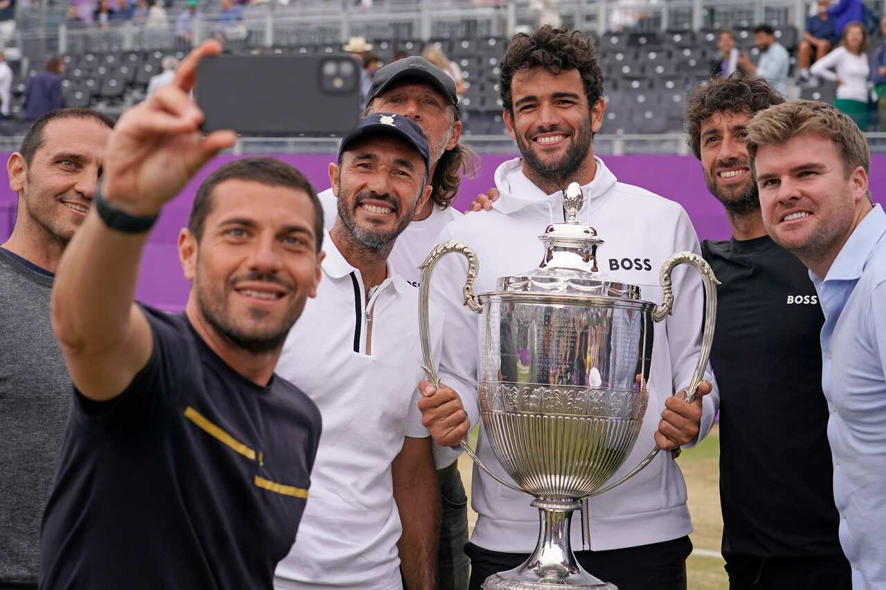 Matteo Berrettini posa con la coppa del Queen's assieme ai componenti del suo team e a papà Luca (sullo sfondo)