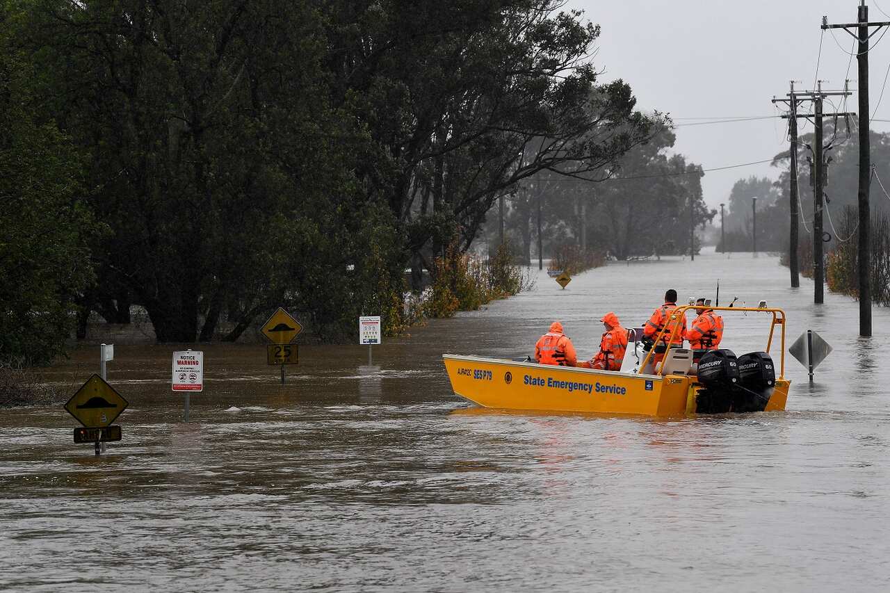 A NSW State Emergency Service (SES) crew is seen in a rescue boat as roads are submerged under floodwater from the swollen Hawkesbury River, in Windsor,