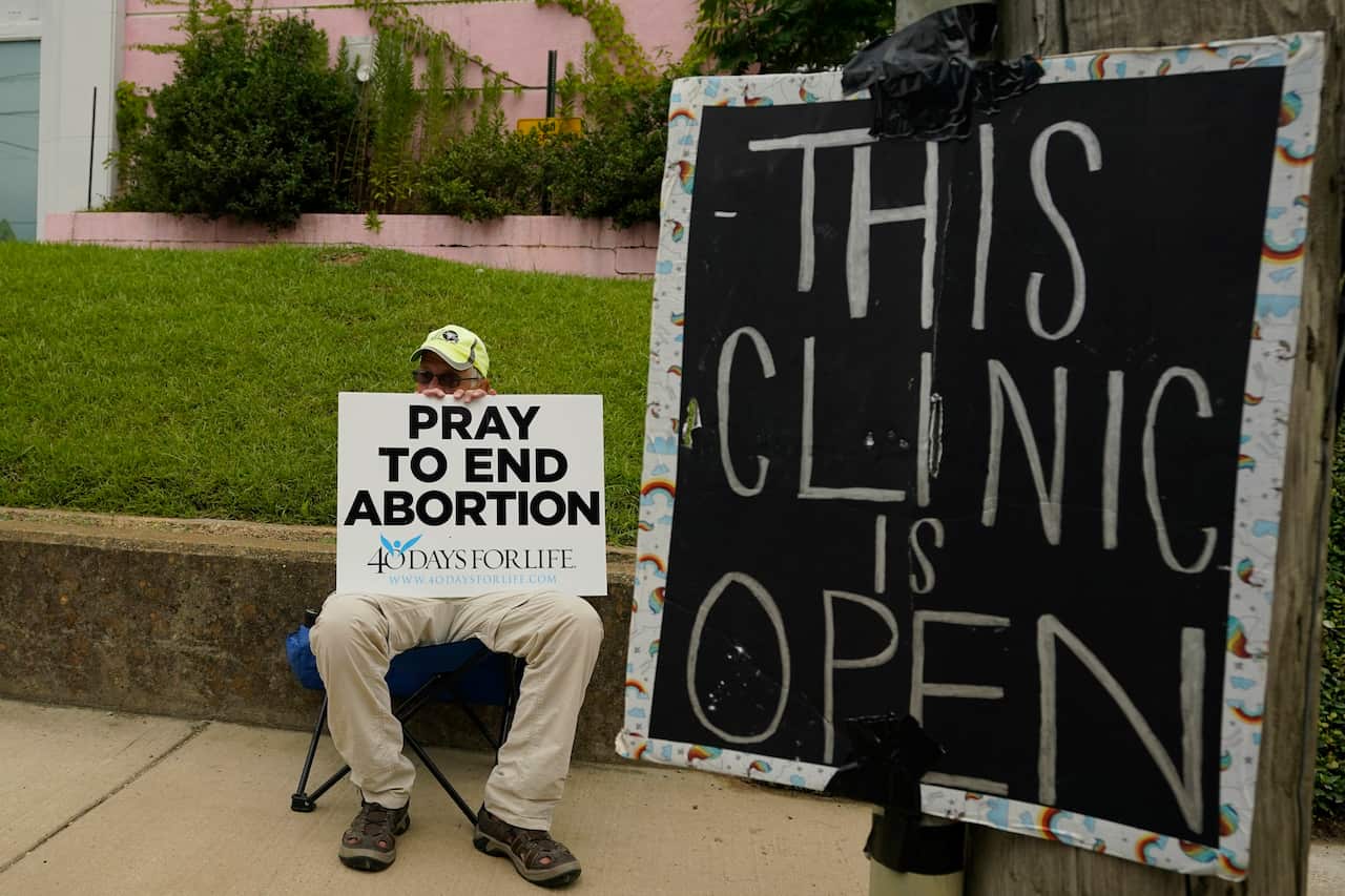 An anti-abortion supporter sits behind a sign 