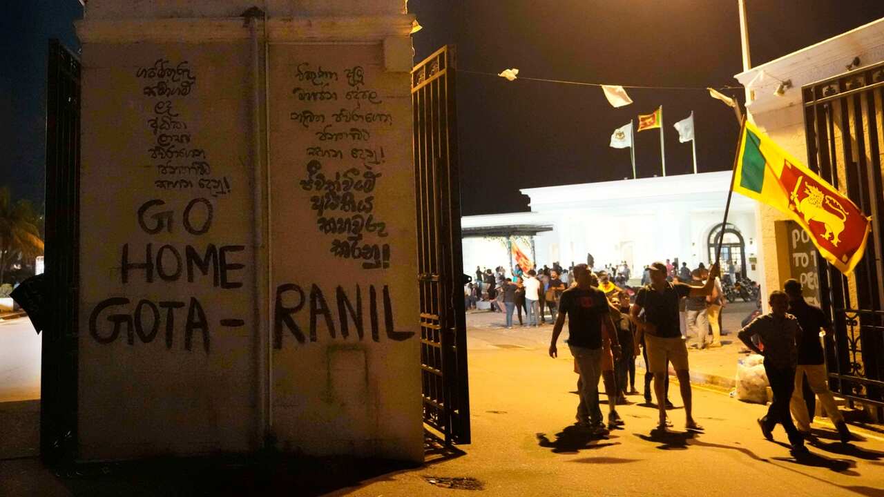 Protesters walk past a vandalised security gate at the entrance to president's official residence in Colombo, Sri Lanka, Saturday, July 9, 2022. 