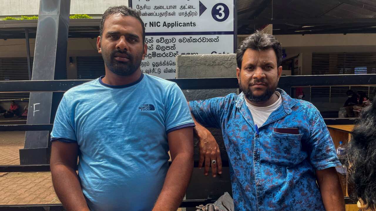 Sri Lankan man Mohamed Ishad, left, and his relative Mohamed Fahim wait outside an immigration office to get their passports renewed in Colombo, Sri Lanka, July 14, 2022.
