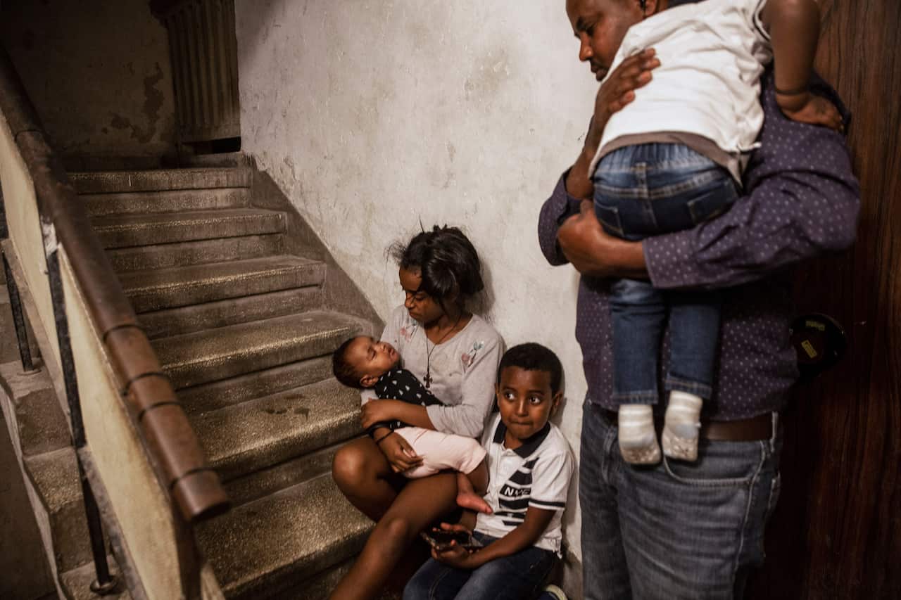 An Eritrean asylum seeker and his children take shelter outside their apartment in Ashdod, Israel, during a siren warning of rockets fired from Gaza.