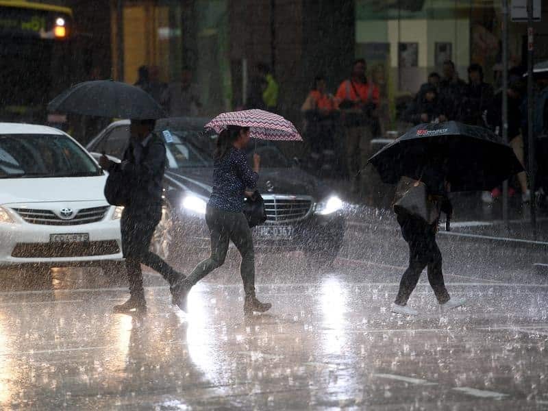 Pedestrians are seen as heavy rain fall.
