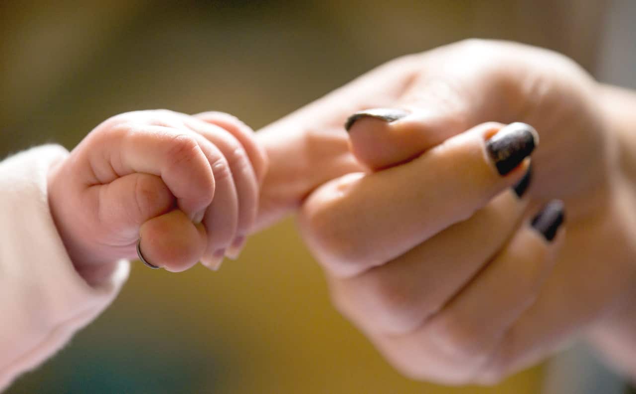 File photo of a baby holding the finger of its mother.