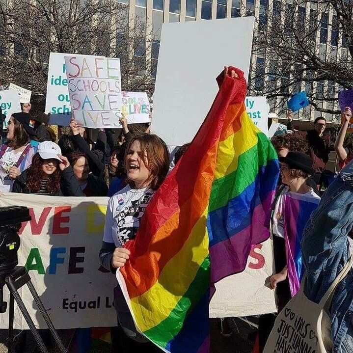 Image of Jill Moran holding a rainbow flag from a rally 