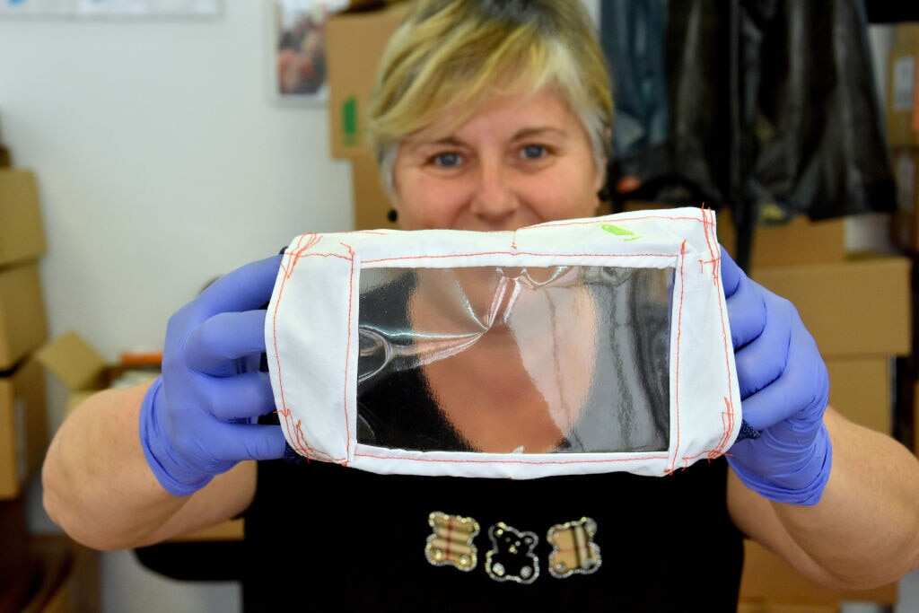 A volunteer shows a transparent cloth face mask for people