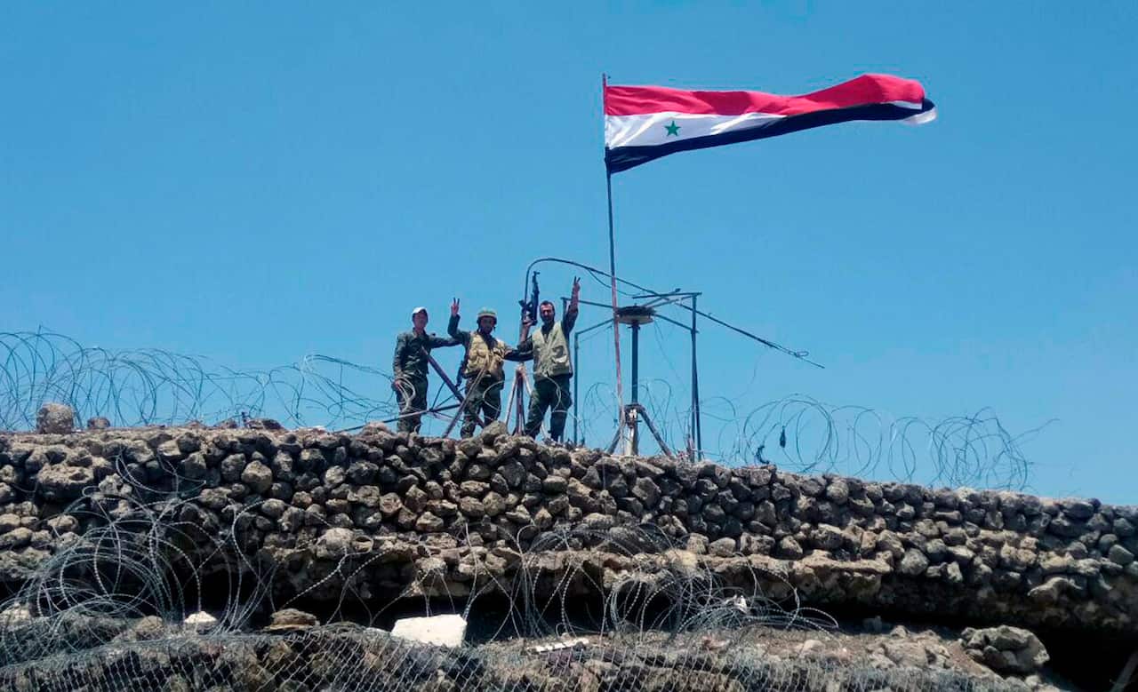 File photo: Syrian troops flash the victory sign next to the Syrian flag in Tell al-Haara, the highest hill in the southwestern Daraa province, Syria