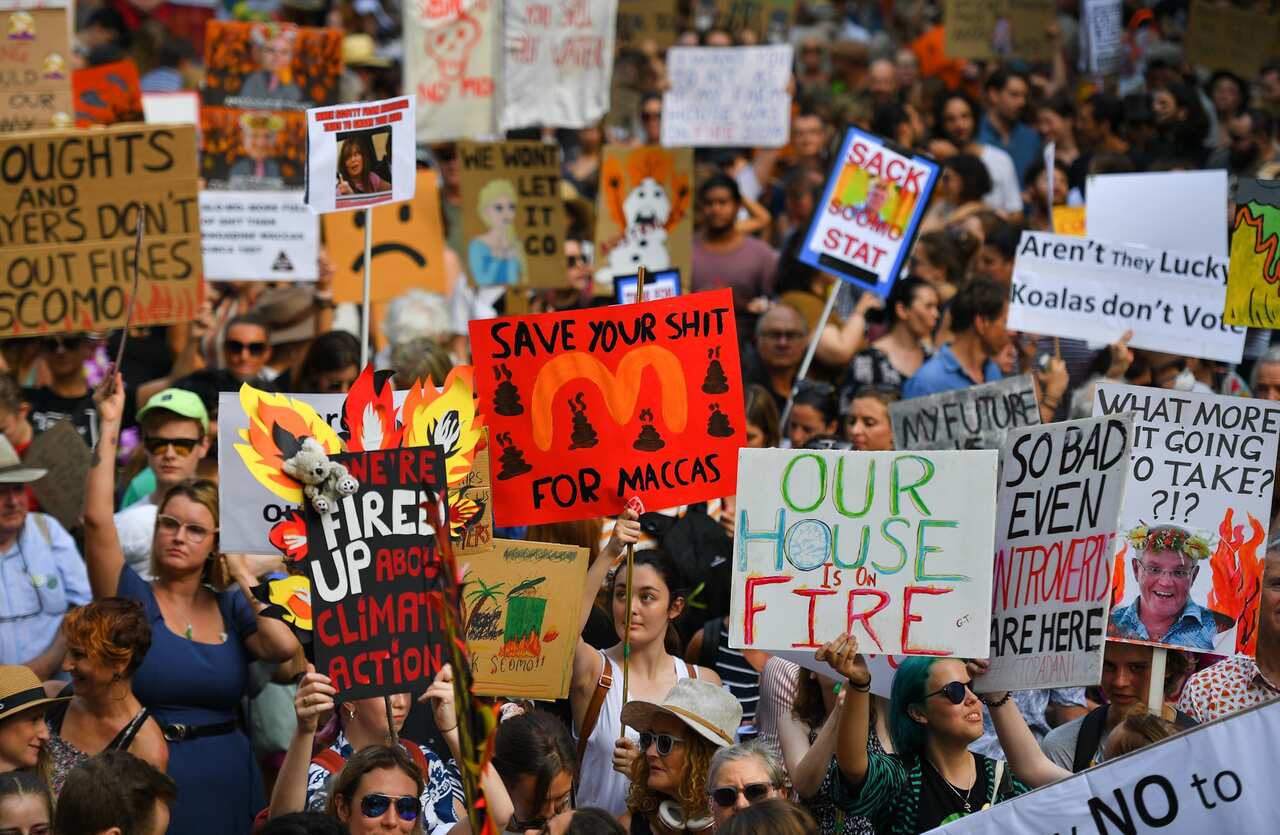 Protesters hold placards during a climate change rally in Sydney, 10 January, 2020. 