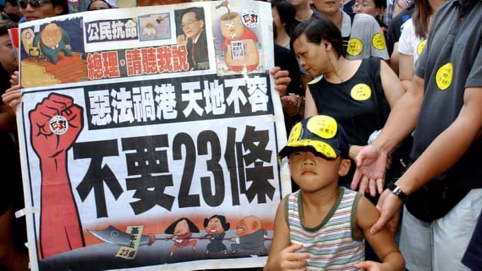 A young protester joins protesters with a banner which reads.,"Evil law spells disaster for Hong Kong" and "No article 23" as they prepare to march from a downtown park to Hong Kong's government offices Tuesday, July 1, 2003, to protest a planned anti-sub
