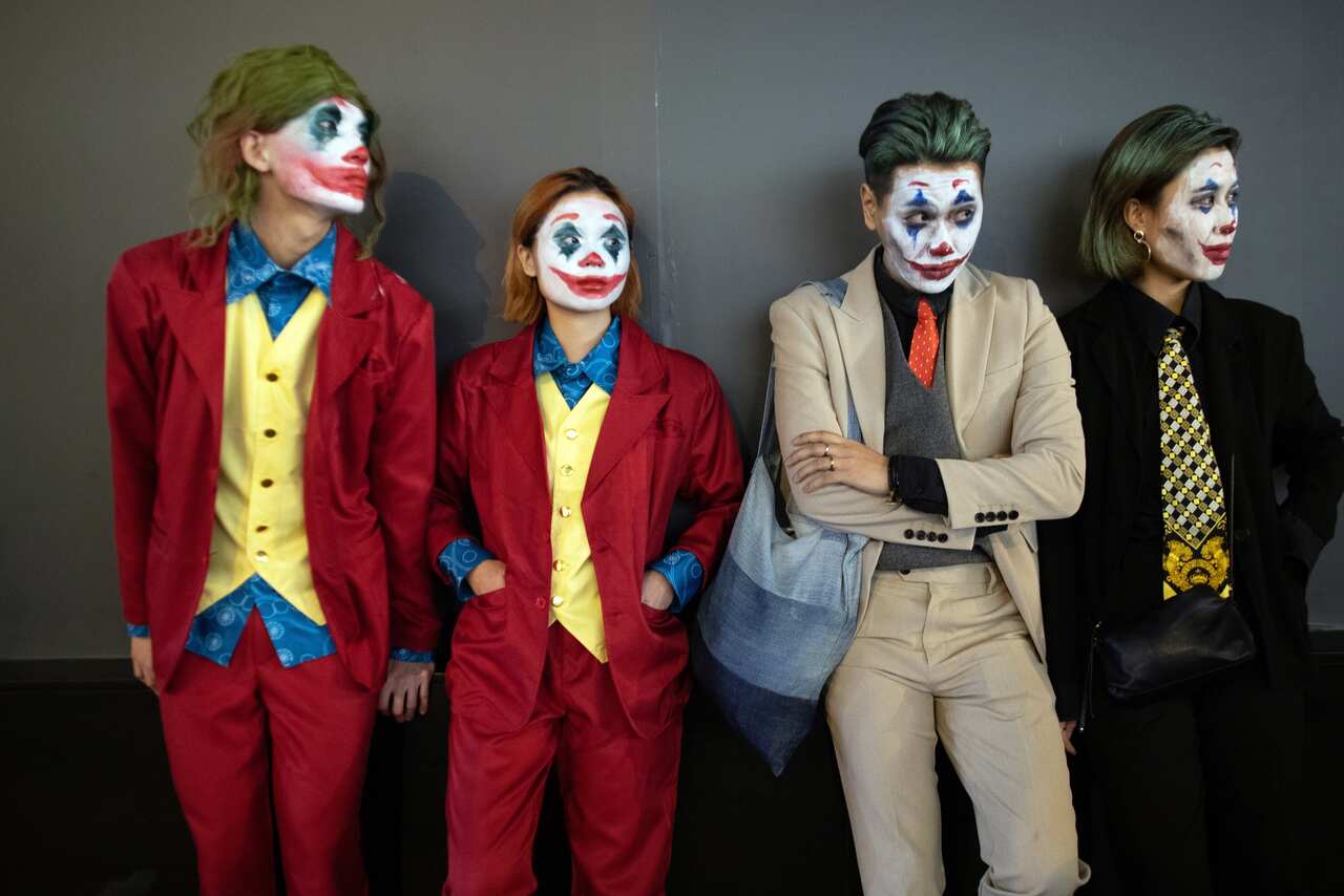 A group of revelers dressed as Jokers watch police disperse protesters. Hong Kong has officially enacted laws banning masks and face paint.