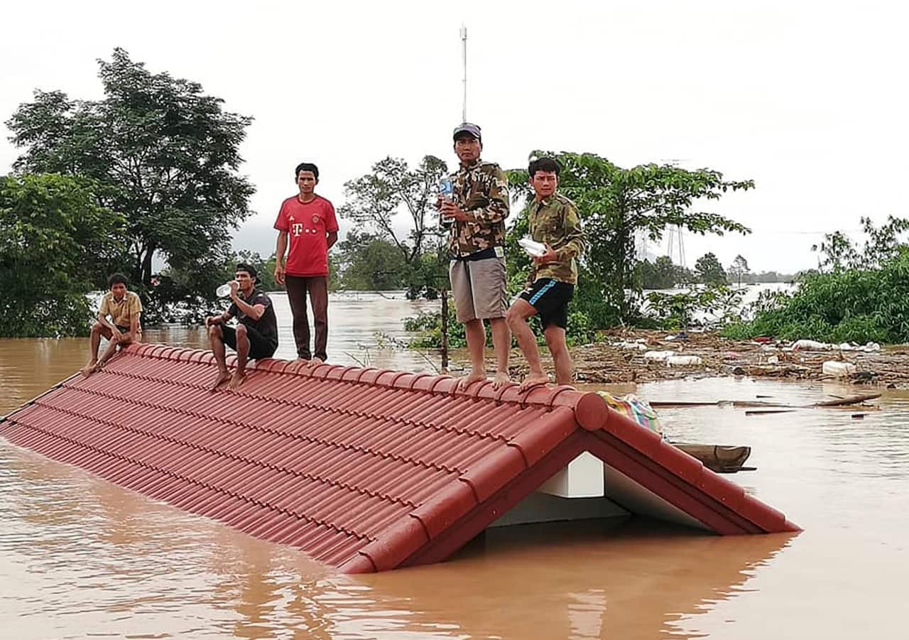 Villagers take refuge on a rooftop above flood waters from a collapsed dam in the Attapeu district of southeastern Laos, Tuesday, July 24, 2018. 
