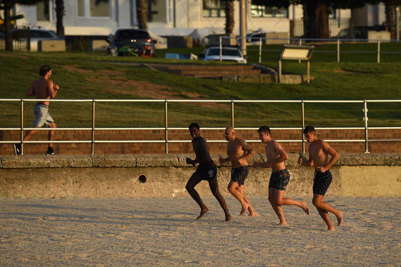 A group of men go for a beach run at sunrise at Bondi Beach in Sydney on Sunday.