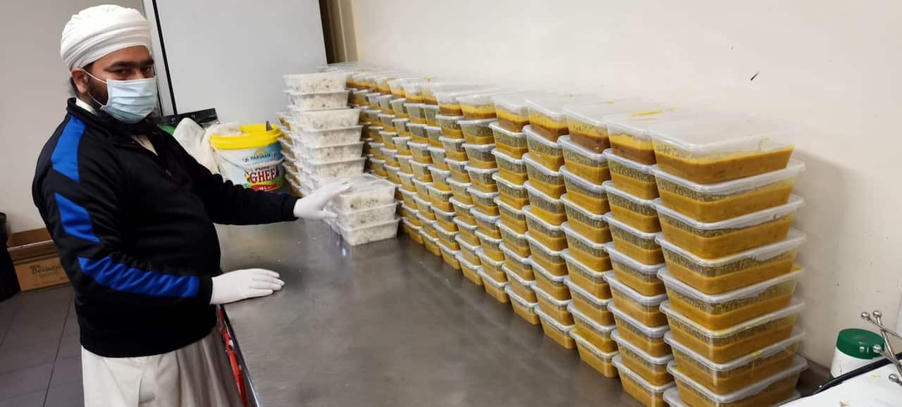 Sikh volunteer preparing containers filled with cooked lentils and rice