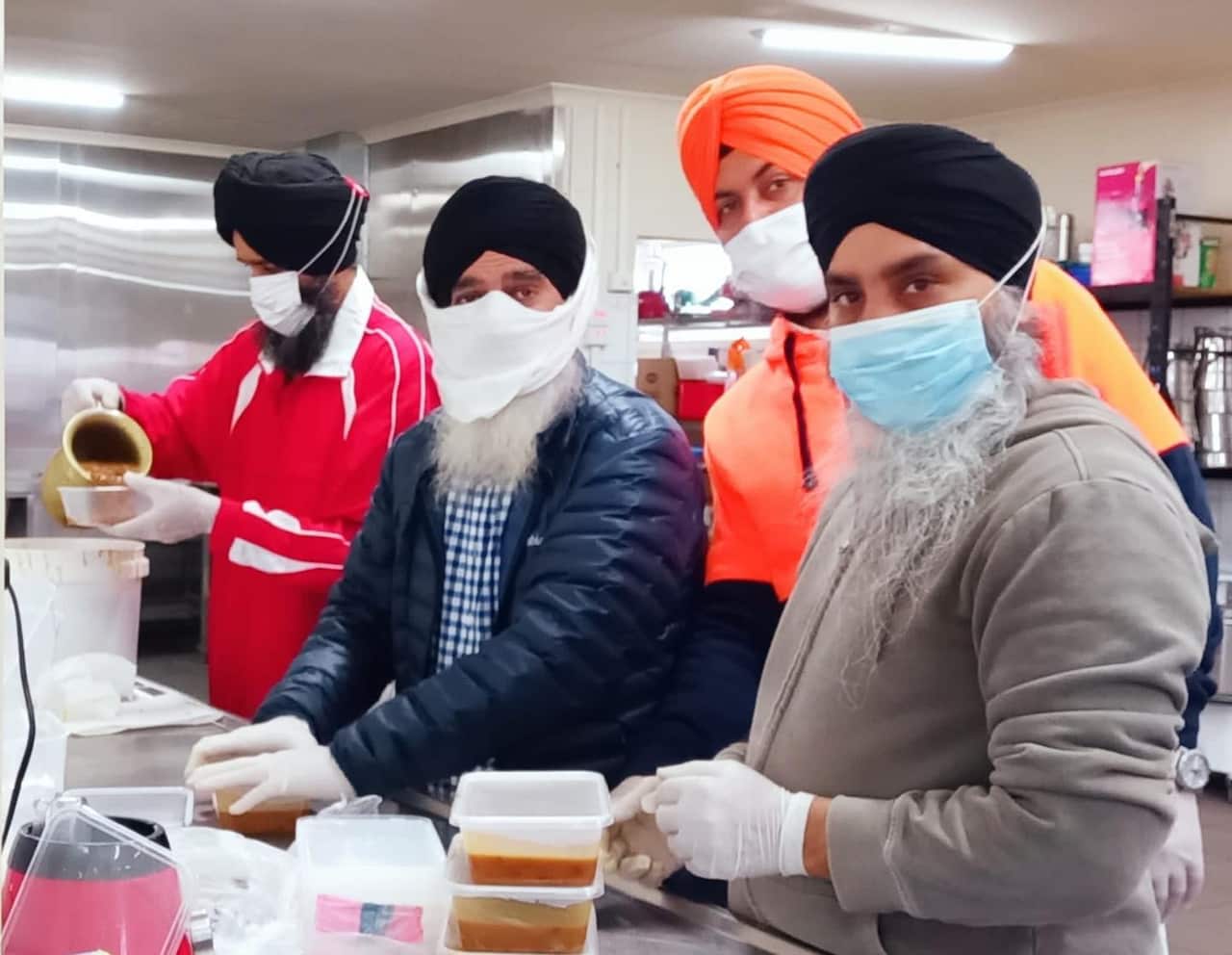 Sikh volunteers packaging food containers for distribution. 