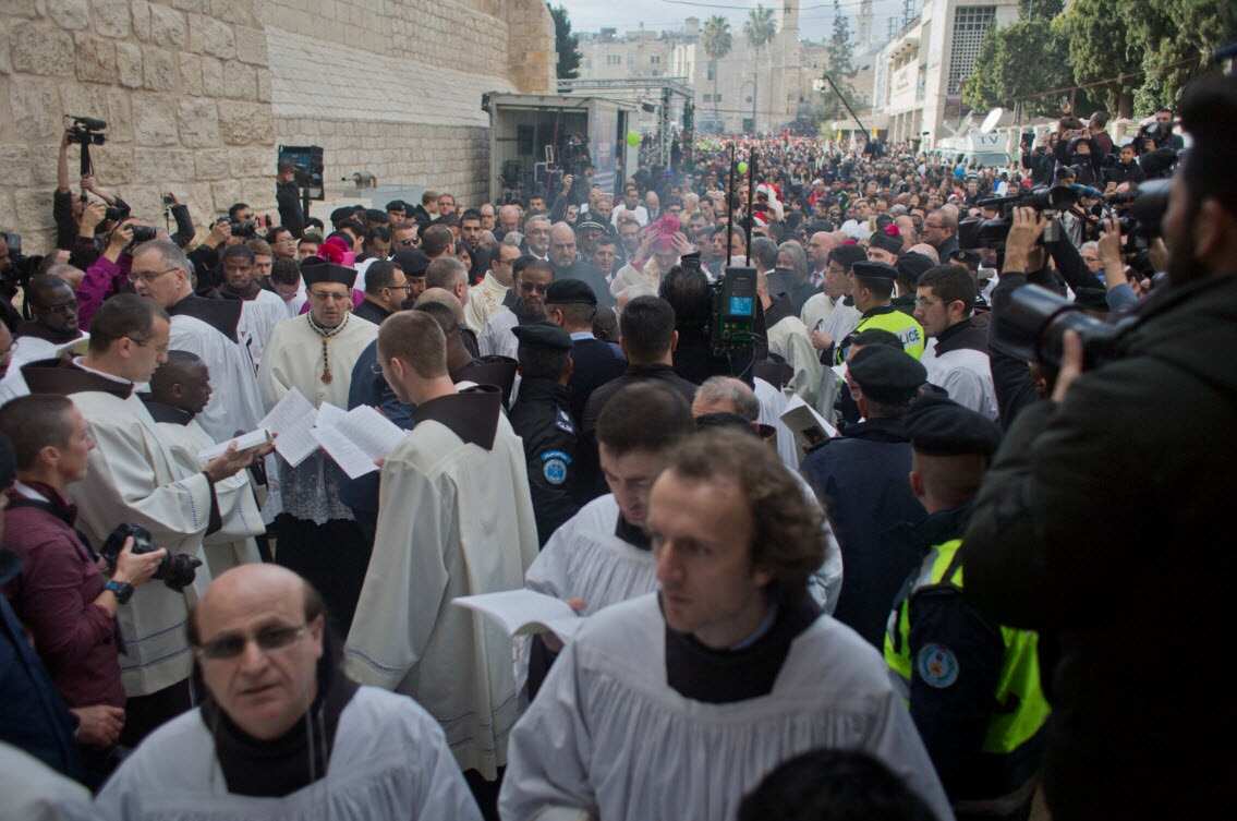 Christians celebrate the arrival of Archbishop Pierbattista Pizzaballa, after he crossed an Israeli military checkpoint from Jerusalem ahead of midnight Mass at the Church of the Nativity in the West Bank city of Bethlehem (AAP)
