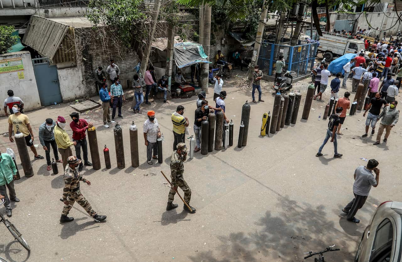 Family members of COVID-19 patients queue with empty oxygen cylinders outside an oxygen filling centre in New Delhi.