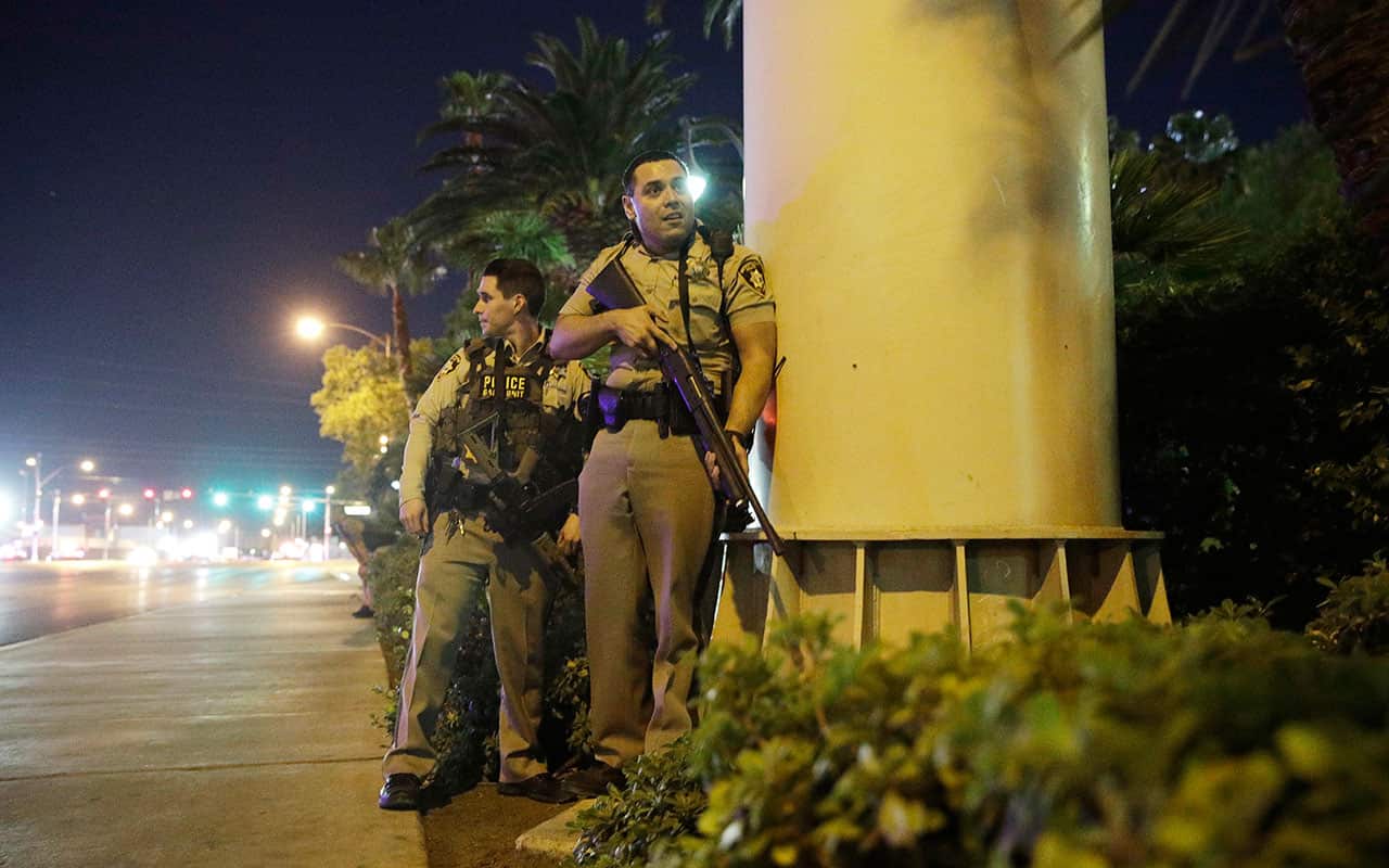 Police officers take cover near the scene of a shooting near the Mandalay Bay resort and casino on the Las Vegas Strip, Sunday, Oct. 1, 2017, in Las Vegas. 