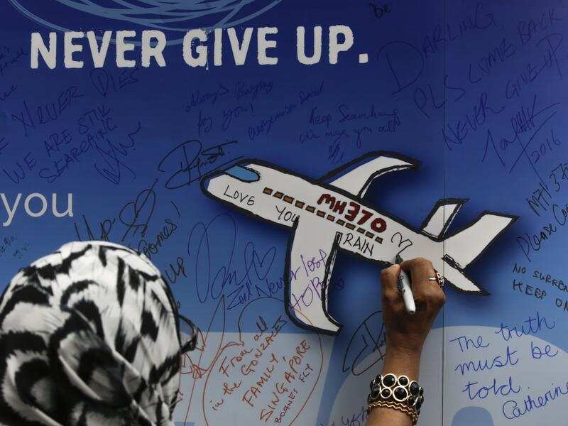 A woman writes messages on a banner for missing flight MH370.