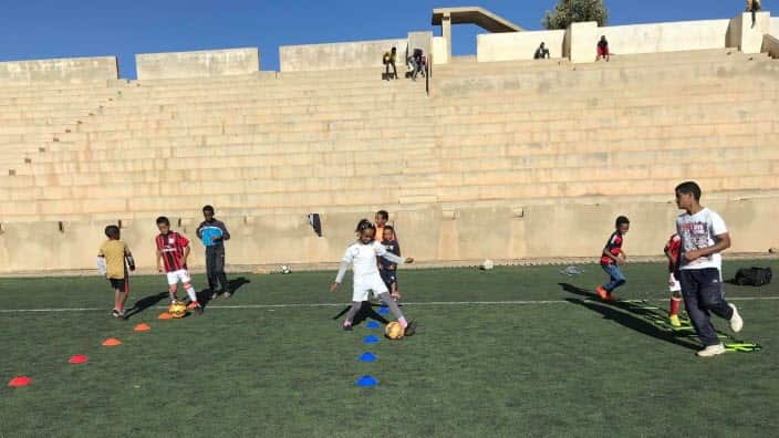 Kids playing soccer with the support of One Ball.
