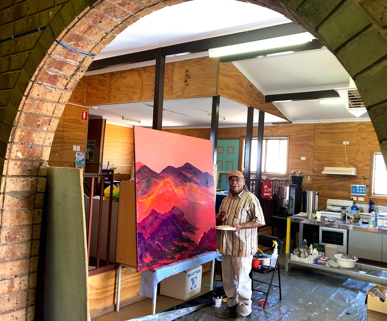 Artist George Cooley at work on a painting inspired by the Painted Desert Countryin the Umoona Council office.