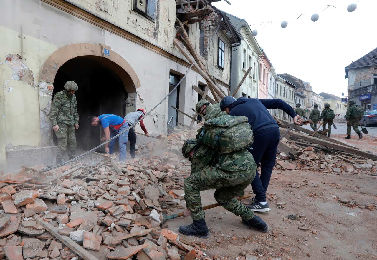 Croatian military personnel and civilians clear the debris from buildings damaged in an earthquake in Petrinja, Croatia.
