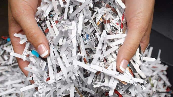 Woman holding heap of shredded paper close-up of hands