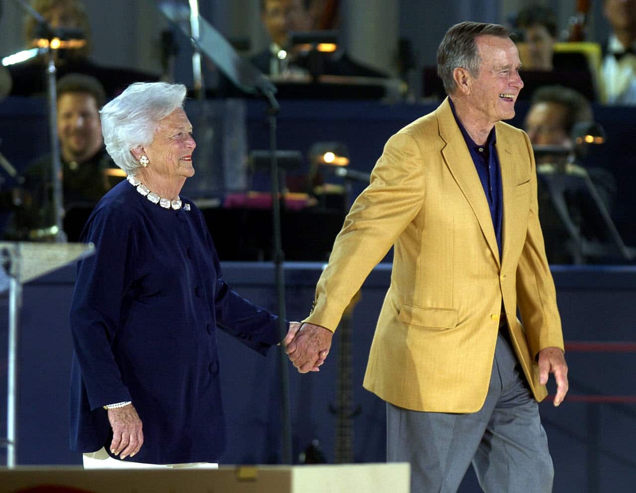 Former US President George H.W. Bush and former First Lady Barbara Bush smile as they are introduced at Bush's 80th birthday celebration in 2004.