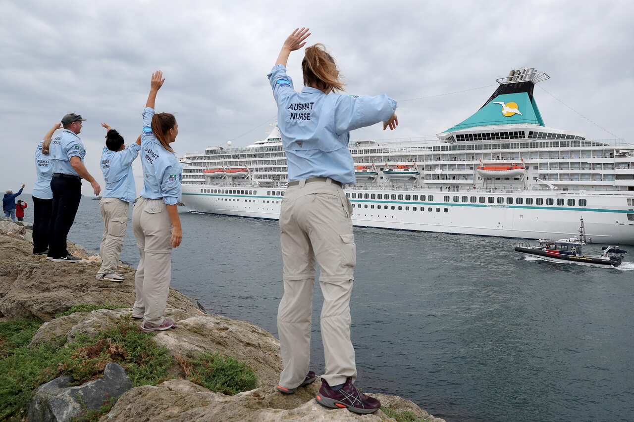 Australian Medical Assistance Team staff who worked with the passengers and crew on the cruise ship Artania wave goodbye as it departs Fremantle harbour.