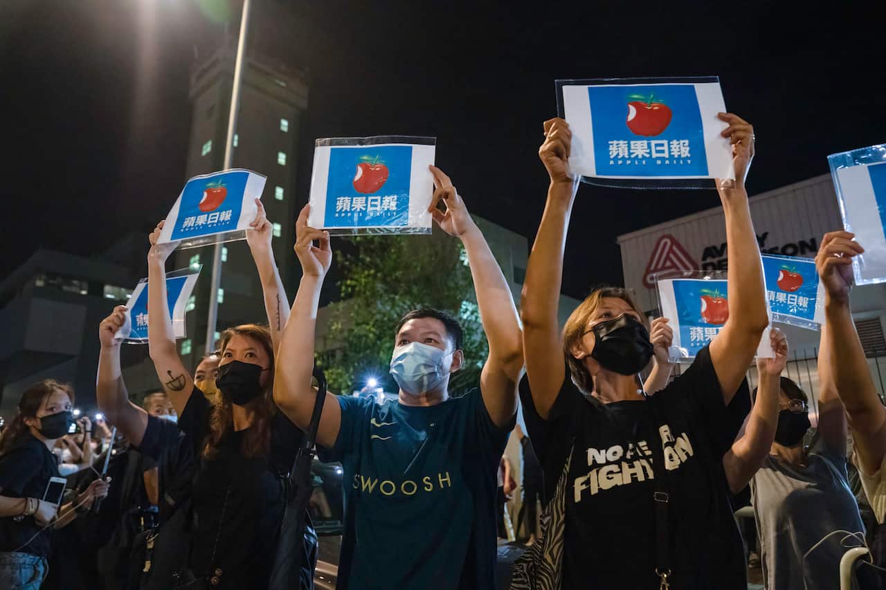 Supporters hold placards in front of the Apple Daily headquarters.