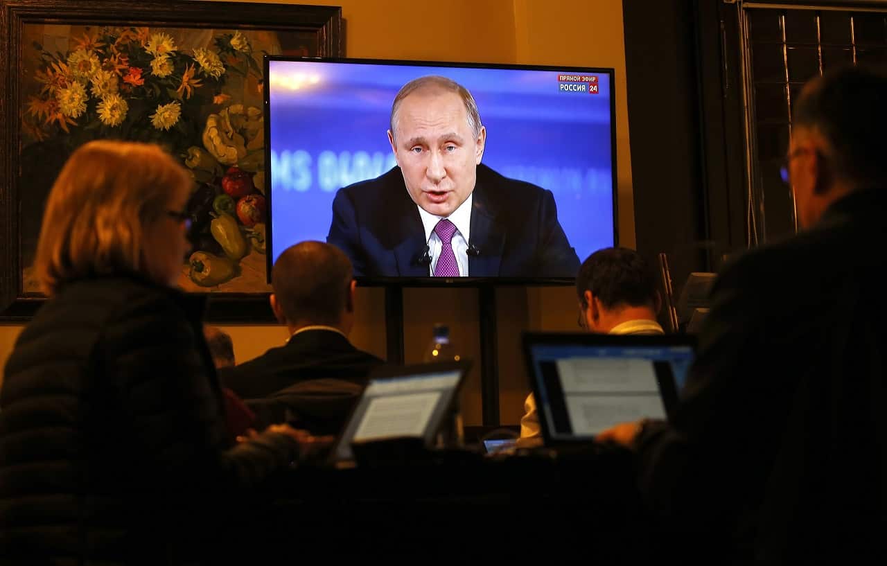Journalists watch Russian President Vladimir Putin speaking on TV during his annual Question and Answer live broadcast 