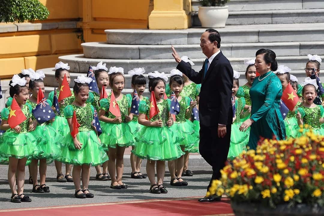 Former Vietnamese President Tran Dai Quang and his wife Nguyen Thi Hien wave to children before welcoming Australia's Governor-General. 