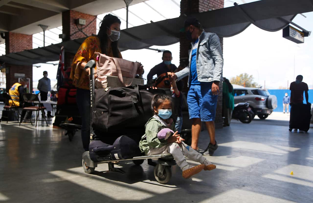 Stranded Australian citizens stand in a queue to board a flight back to their country in Kathmandu, Nepal, Wednesday, May 6, 2020.
