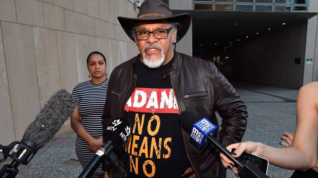 Adrian Burragubba (centre) from the Wangan and Jagalingou traditional owners group speak to the media outside the Federal Court in Brisbane.
