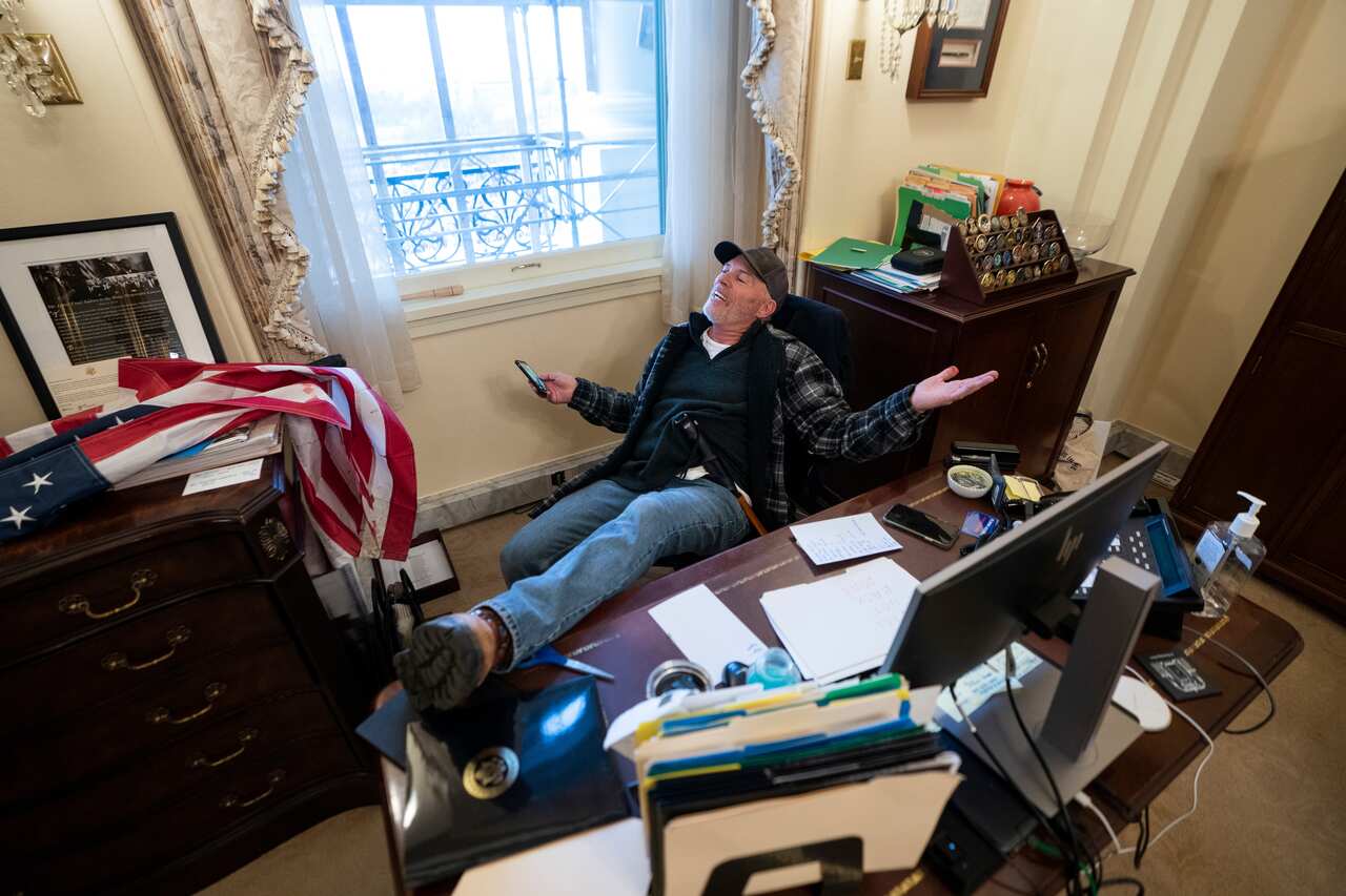 A Trump supporter sits at the desk of US House Speaker Nancy Pelosi