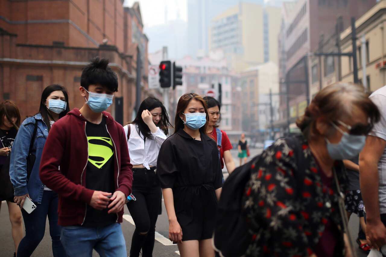 People wear face masks while walking through Sydney