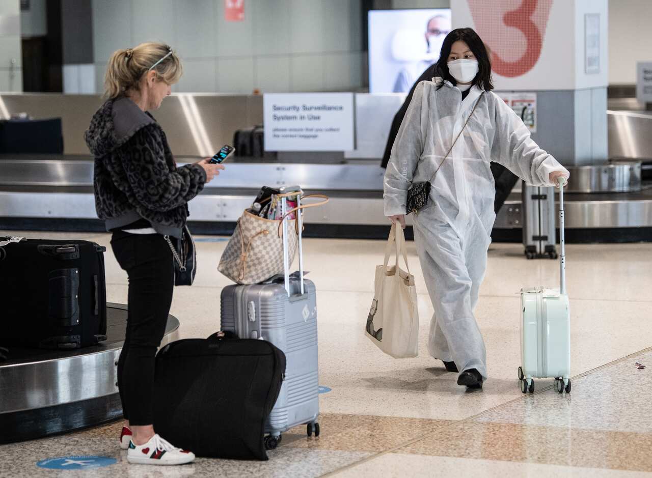 A passenger wearing a protective suit and mask collecting baggage after arriving on a flight from Melbourne at Sydney Airport, 2 July, 2020.