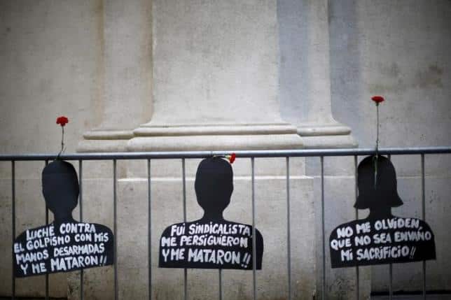 Cut-out depicting victims of human rights abuse during the rule of former dictator Augusto Pinochet hang on a fence next to the "La Moneda" Presidential Palace during a rally in Santiago