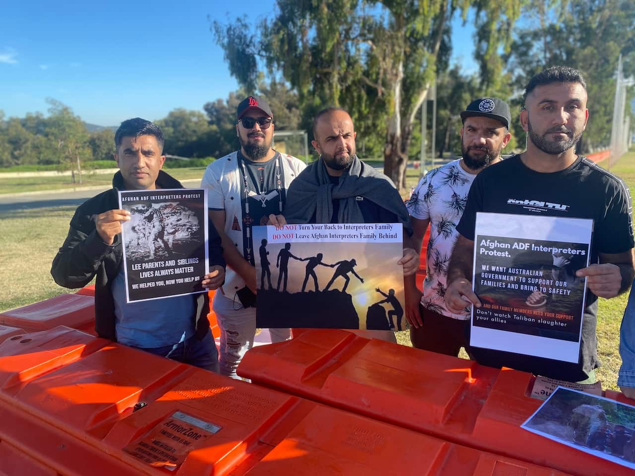 Afghan community members hold signs at the rally.