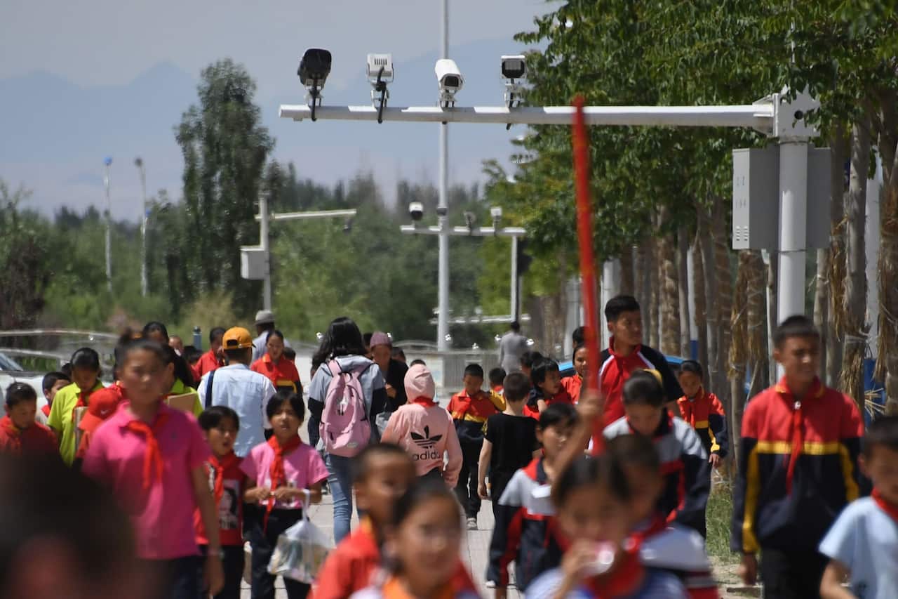 This photo taken on June 4, 2019 shows schoolchildren walking below surveillance cameras in Akto, south of Kashgar, in China's western Xinjiang region. - While Muslims around the world celebrated the end of Ramadan with early morning prayers and festiviti