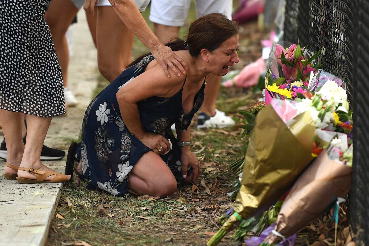 A woman grieves near flowers placed at the scene where seven children were hit on a footpath by a four-wheel drive in the Sydney suburb of Oatlands.