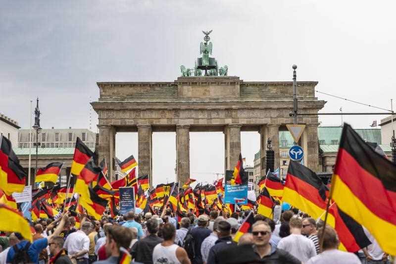 People hold German flags during a rally of the Alternative for Germany (AfD) party at the Brandenburg Gate in Berlin, Germany, 27 May 2018.