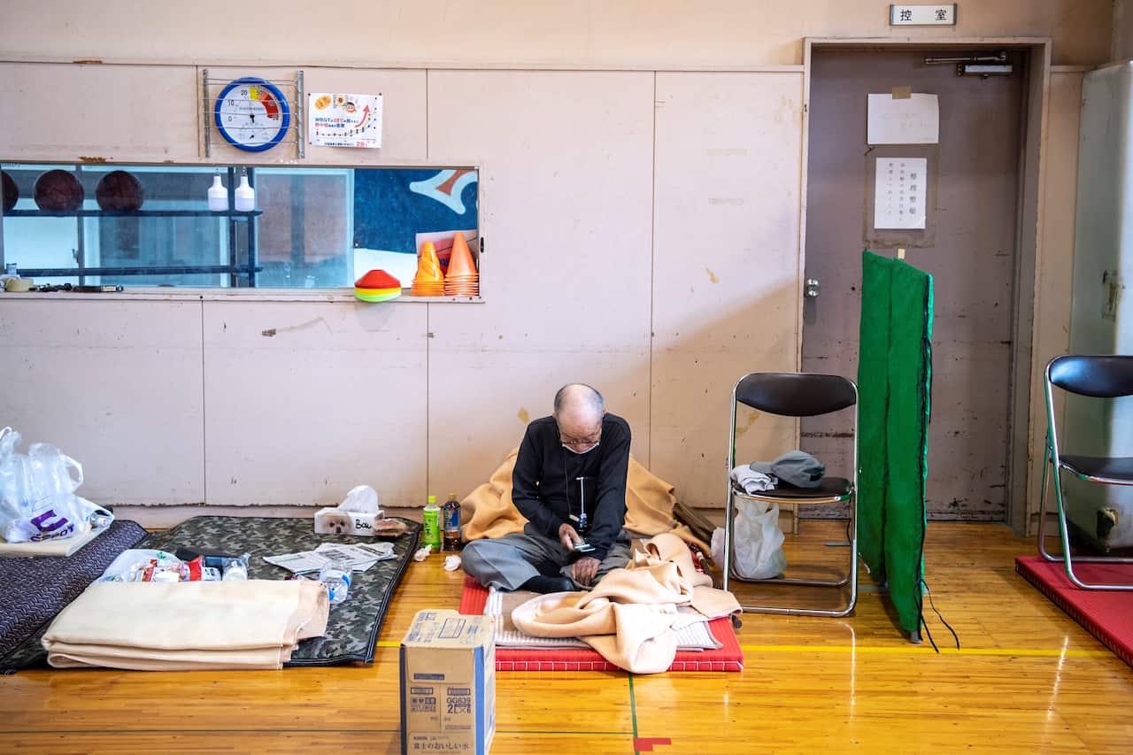A landslide-affected resident sits in an evacuation centre following days of heavy rain in Atami in Shizuoka Prefecture on 4 July 2021.